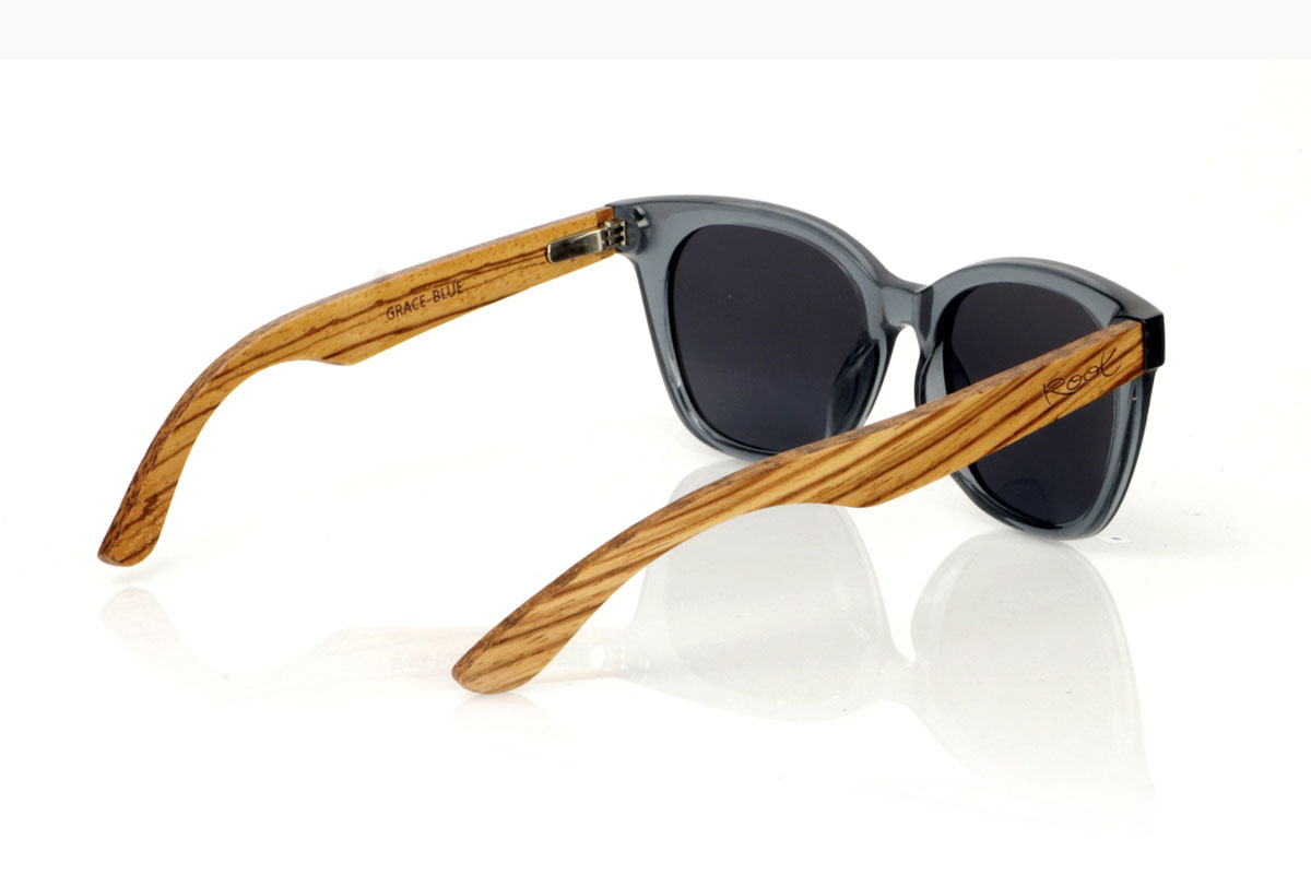 Wood eyewear of Zebrano GRACE BLUE. GRACE BLUE sunglasses: elegant with a contemporary touch. These glasses, with their dark grayish blue frame, have a suggestive shape that combines rounded eyebrows with a narrower bottom, creating a sophisticated and modern look. The Zebrano wood rods provide a natural contrast, highlighting the attention to detail and quality craftsmanship. Available with gray or gradient gray lenses, they offer protection and clarity in any light. With a measurement of 143x49mm and a caliber of 50, the GRACE BLUE are ideal for those looking to stand out with subtlety and elegance. Make every look count. for Wholesale & Retail | Root Sunglasses® 
